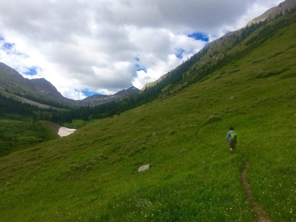 man hiking through high alpine meadow