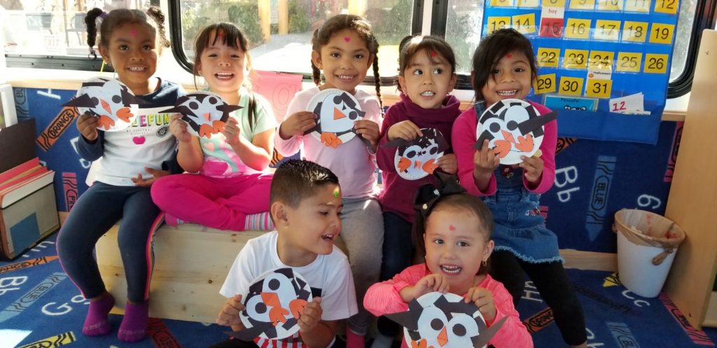 kids posing with penguin crafts