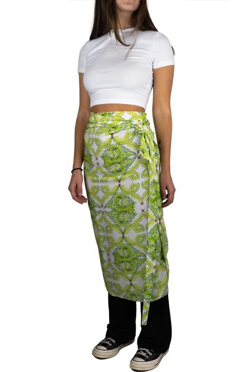 shoulder down image of young woman wearing a white t-shirt and green floral wrap skirt over leggings and converse sneakers